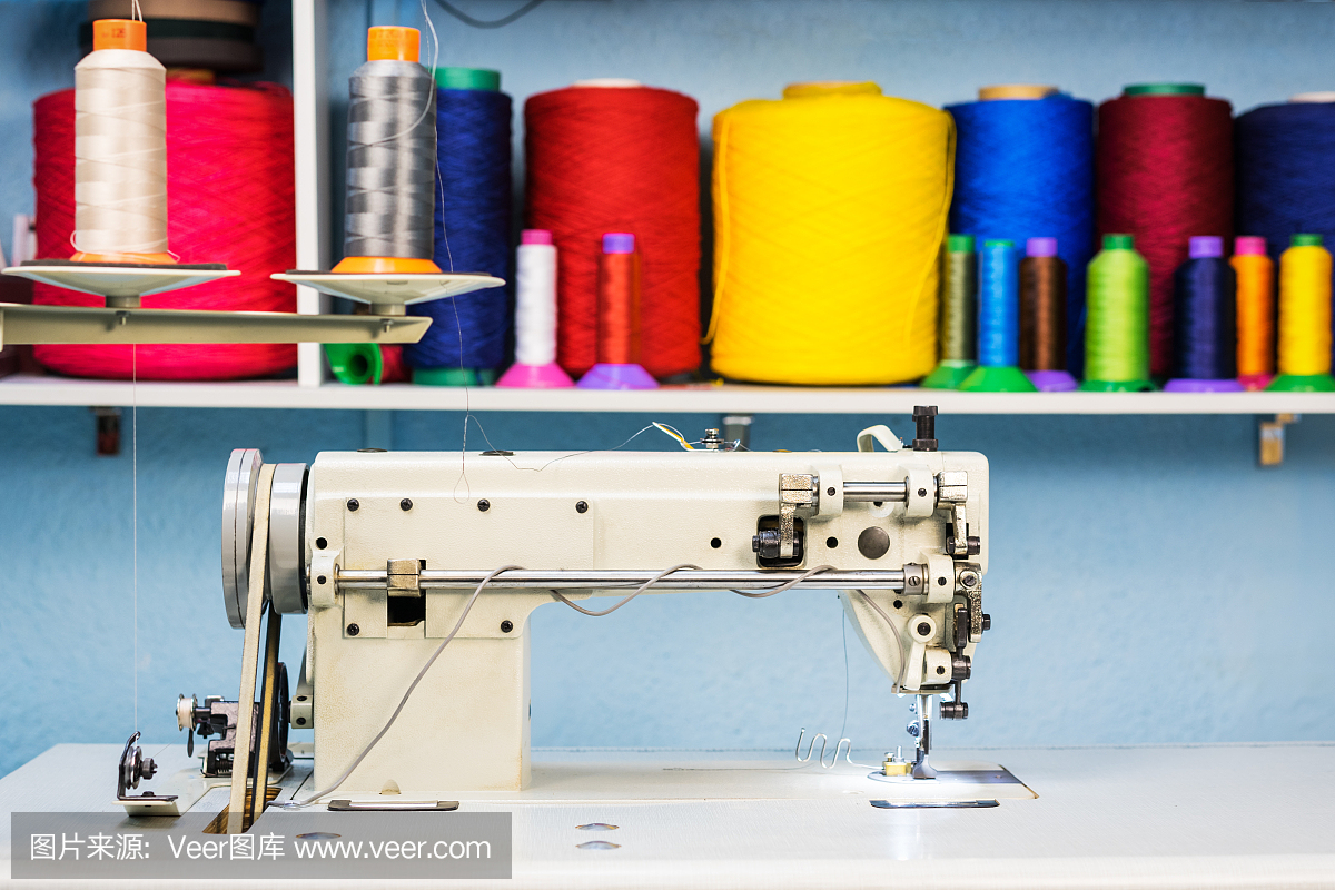 缝纫机包缝机在裁缝车间的背景与彩色线的架子